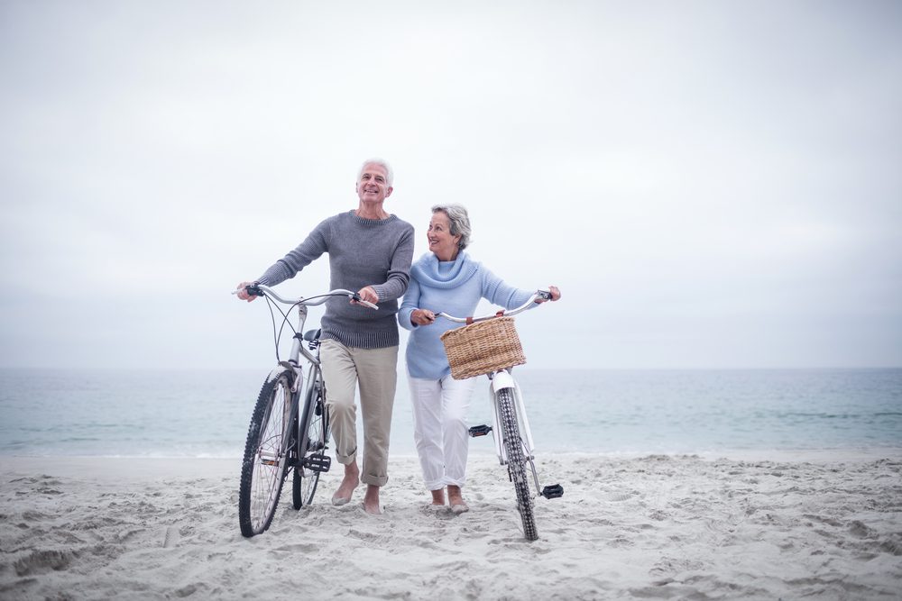 Senior,Couple,Having,Ride,With,Their,Bike,On,The,Beach